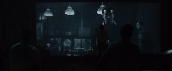 Movie still from “Reminiscence” (2021), directed by Lisa Joy – A man standing in front of a screen in a room; Wide shot, Over the shoulder angle