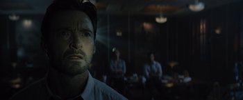 Movie still from “Reminiscence” (2021), directed by Lisa Joy – A man in a room with a group of people in the background; Close Up shot, Low angle