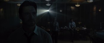 Movie still from “Reminiscence” (2021), directed by Lisa Joy – A group of people standing in a dark room; Medium shot, Over the shoulder angle