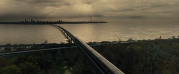 Movie still from “Reminiscence” (2021), directed by Lisa Joy – A train traveling over a bridge next to a body of water; Extreme Wide shot, High angle