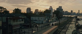 Movie still from “Reminiscence” (2021), directed by Lisa Joy – A person sitting on the side of a road near some buildings; Extreme Wide shot, Low angle