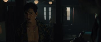 Movie still from “Reminiscence” (2021), directed by Lisa Joy – A man in a hawaiian shirt is sitting in a dimly - lit room; Medium shot, Over the shoulder angle