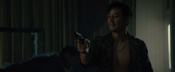 Movie still from “Reminiscence” (2021), directed by Lisa Joy – A man holding a gun while standing next to another man; Medium shot, Over the shoulder angle