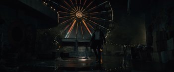 Movie still from “Reminiscence” (2021), directed by Lisa Joy – A man walking in front of a ferris wheel at night; Extreme Wide shot, Low angle