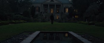 Movie still from “Reminiscence” (2021), directed by Lisa Joy – A man standing in front of a large house at night; Extreme Wide shot, Low angle
