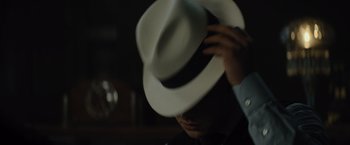 Movie still from “Reminiscence” (2021), directed by Lisa Joy – A man wearing a white hat in a dark room; Extreme Close Up shot, Over the shoulder angle