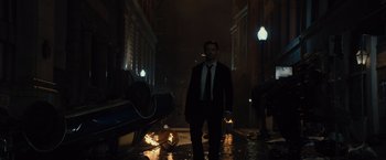Movie still from “Reminiscence” (2021), directed by Lisa Joy – A man wearing a suit and tie walking down a street; Wide shot, Low angle