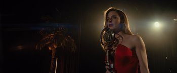 Movie still from “Reminiscence” (2021), directed by Lisa Joy – A woman in a red dress is holding a microphone; Medium shot, Low angle