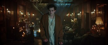 Movie still from “Renfield” (2023), directed by Chris McKay – A man in a robe standing in a dimly - lit room; Medium shot, Low angle