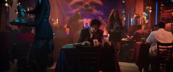 Movie still from “Renfield” (2023), directed by Chris McKay – A man sitting at a table in front of a woman; Wide shot, Over the shoulder angle