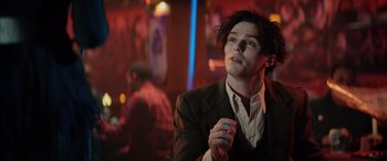 Movie still from “Renfield” (2023), directed by Chris McKay – A man in a suit holding a nintendo wii game controller; Close Up shot, Over the shoulder angle