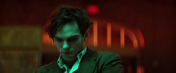 Movie still from “Renfield” (2023), directed by Chris McKay – A man in a green suit looking down at his face; Close Up shot, Low angle