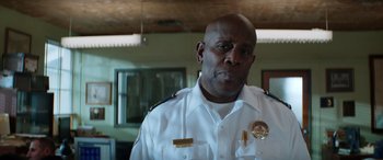 Movie still from “Renfield” (2023), directed by Chris McKay – A man in a police uniform is standing in a room; Close Up shot, Low angle