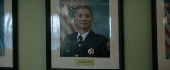 Movie still from “Renfield” (2023), directed by Chris McKay – A framed picture of a police officer in front of an american flag; Close Up shot, Low angle