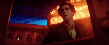 Movie still from “Renfield” (2023), directed by Chris McKay – A man in a suit standing in front of neon signs; Close Up shot, Low angle