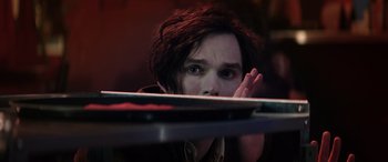 Movie still from “Renfield” (2023), directed by Chris McKay – A young man looking over a table at the camera; Close Up shot, Over the shoulder angle