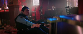 Movie still from “Renfield” (2023), directed by Chris McKay – A man sitting in a room holding a gun; Medium shot, Low angle