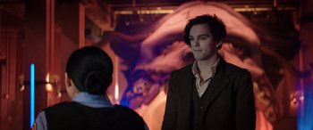 Movie still from “Renfield” (2023), directed by Chris McKay – A man standing next to a woman in front of a painting; Medium shot, Over the shoulder angle