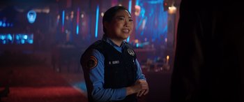 Movie still from “Renfield” (2023), directed by Chris McKay – A police officer smiling for the camera in the dark; Close Up shot, Over the shoulder angle