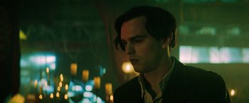 Movie still from “Renfield” (2023), directed by Chris McKay – A man with long dark hair standing in front of candles in a dark room; Close Up shot, Low angle
