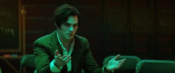 Movie still from “Renfield” (2023), directed by Chris McKay – A man in a green suit claps his hands; Medium shot, Low angle