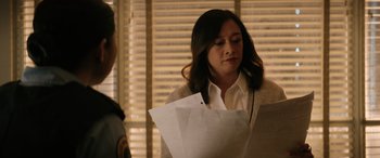 Movie still from “Renfield” (2023), directed by Chris McKay – A woman holding a piece of paper in front of a man; Close Up shot, Over the shoulder angle