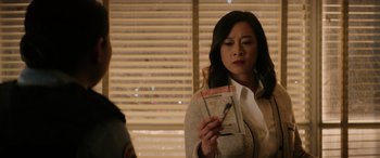 Movie still from “Renfield” (2023), directed by Chris McKay – A woman looking at a piece of paper in front of a window; Close Up shot, Over the shoulder angle