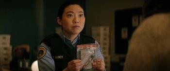 Movie still from “Renfield” (2023), directed by Chris McKay – A woman in a uniform holding a package of scissors; Close Up shot, Over the shoulder angle