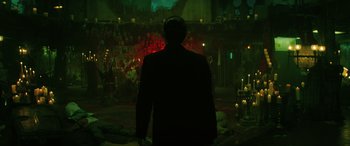 Movie still from “Renfield” (2023), directed by Chris McKay – A man standing in front of a stage lit up with candles; Wide shot, Low angle