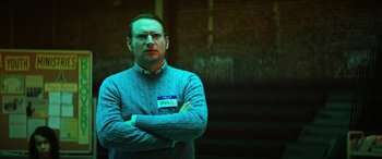 Movie still from “Renfield” (2023), directed by Chris McKay – A man in a sweater with his arms crossed; Medium shot, Low angle