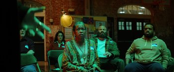 Movie still from “Renfield” (2023), directed by Chris McKay – A group of people sitting in a room; Medium shot, Low angle