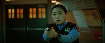 Movie still from “Renfield” (2023), directed by Chris McKay – A police officer holding a gun in a room; Close Up shot, Low angle