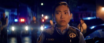 Movie still from “Renfield” (2023), directed by Chris McKay – A police officer is standing in front of some lights; Close Up shot, Over the shoulder angle