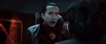 Movie still from “Renfield” (2023), directed by Chris McKay – A person wearing a suit and tie; Close Up shot, Over the shoulder angle