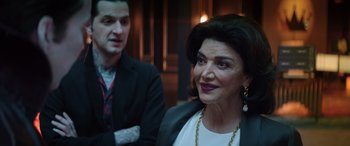 Movie still from “Renfield” (2023), directed by Chris McKay – A man standing next to an older woman in a suit; Close Up shot, Over the shoulder angle