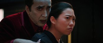 Movie still from “Renfield” (2023), directed by Chris McKay – A man and a woman standing next to each other in front of a building; Close Up shot, Over the shoulder angle