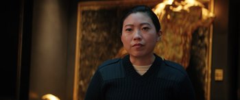 Movie still from “Renfield” (2023), directed by Chris McKay – A woman wearing a black sweater standing in front of a painting; Close Up shot, Low angle