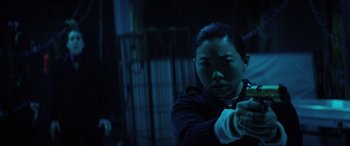 Movie still from “Renfield” (2023), directed by Chris McKay – A person holding a gun in a dark room; Medium shot, Low angle