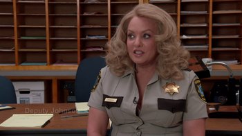 Movie still from “Reno 911!: The Hunt for QAnon” (2021), directed by Robert Ben Garant – A woman with blonde hair wearing a sheriff's uniform; Close Up shot, Over the shoulder angle