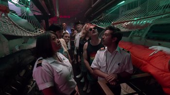 Movie still from “Reno 911!: The Hunt for QAnon” (2021), directed by Robert Ben Garant – A group of people standing around in a room; Wide shot, High angle