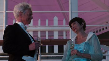 Movie still from “Reno 911!: The Hunt for QAnon” (2021), directed by Robert Ben Garant – A man and a woman holding wine glasses; Medium shot, Over the shoulder angle