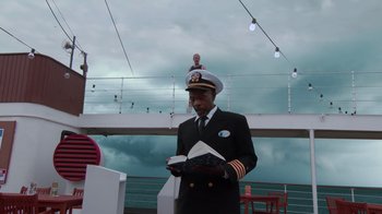 Movie still from “Reno 911!: The Hunt for QAnon” (2021), directed by Robert Ben Garant – A man in a uniform is holding a book; Medium shot, Low angle