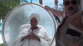 Movie still from “Reno 911!: The Hunt for QAnon” (2021), directed by Robert Ben Garant – A woman in a white turban is in a mirror; Medium shot, Over the shoulder angle