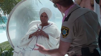 Movie still from “Reno 911!: The Hunt for QAnon” (2021), directed by Robert Ben Garant – A woman in a white robe is talking to a cop; Medium shot, Over the shoulder angle