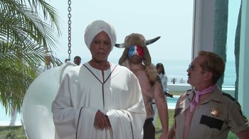 Movie still from “Reno 911!: The Hunt for QAnon” (2021), directed by Robert Ben Garant – A woman in a white robe and a man in a bull mask; Medium shot, Over the shoulder angle