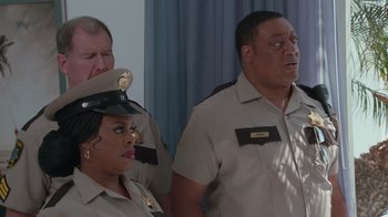 Movie still from “Reno 911!: The Hunt for QAnon” (2021), directed by Robert Ben Garant – A group of people standing next to each other in uniform; Medium shot, Over the shoulder angle