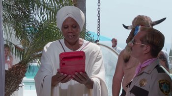Movie still from “Reno 911!: The Hunt for QAnon” (2021), directed by Robert Ben Garant – An older woman holding a tablet in her hands; Medium shot, Over the shoulder angle