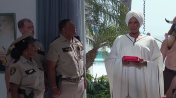 Movie still from “Reno 911!: The Hunt for QAnon” (2021), directed by Robert Ben Garant – A couple of men standing next to each other in front of palm trees; Medium shot, Over the shoulder angle
