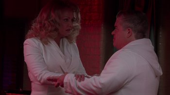 Movie still from “Reno 911!: The Hunt for QAnon” (2021), directed by Robert Ben Garant – A man and a woman in a white suit; Medium shot, Over the shoulder angle