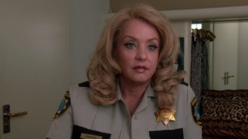 Movie still from “Reno 911!: The Hunt for QAnon” (2021), directed by Robert Ben Garant – A woman with blonde hair wearing a sheriff's uniform; Close Up shot, Over the shoulder angle
